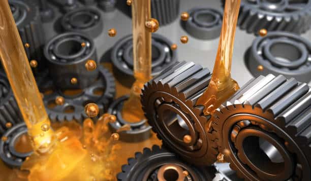 "Oil being poured over metal gears and cogs, illustrating machinery lubrication."