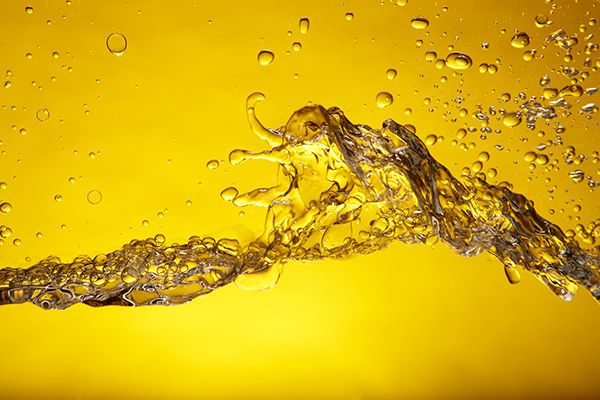 "Dynamic close-up of golden liquid with bubbles forming a wave-like pattern against a vibrant yellow background."
