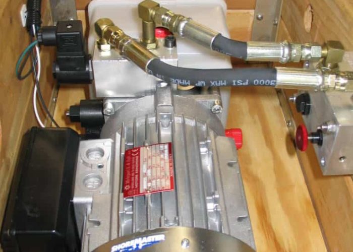 "Industrial equipment setup with a motor, various brass fittings, and electrical components on a wooden frame."